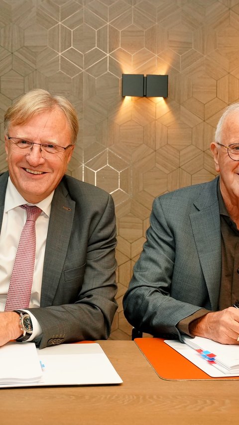 Twee mannen die lachend de camera inkijken