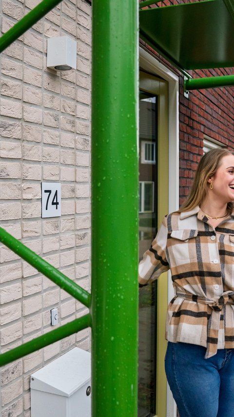 Bewoonster Inez van den Bos staat voor haar nieuwe woning in Eindhoven.
