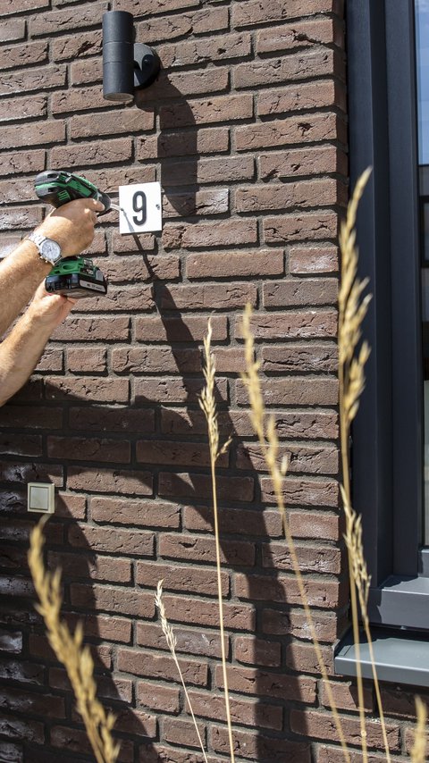 Bewoner boort in muur van Heijmans Huismerk conceptwoning in Waalwijk.jpg