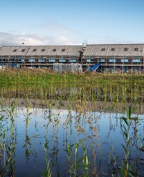 Bouw van de 16 horizon-woningen in Nuenen. Op de voorgrond zie je een plas.