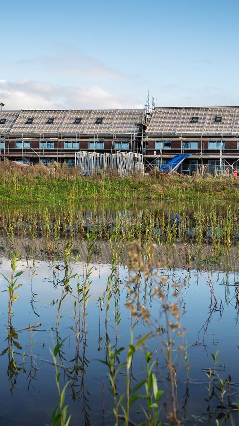 Bouw van de 16 horizon-woningen in Nuenen. Op de voorgrond zie je een plas.