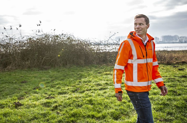 Jaap Wieringa in een oranje jas in een groen veld.