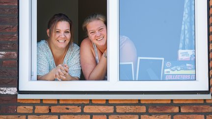 Vrouwen lachen uit het raam van conceptwoning Heijmans Huismerk.jpg